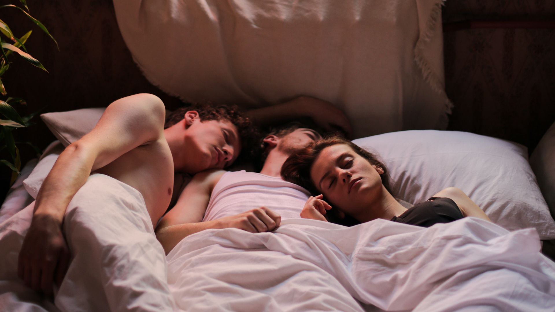 deux hommes et une femme allongés dans un lit