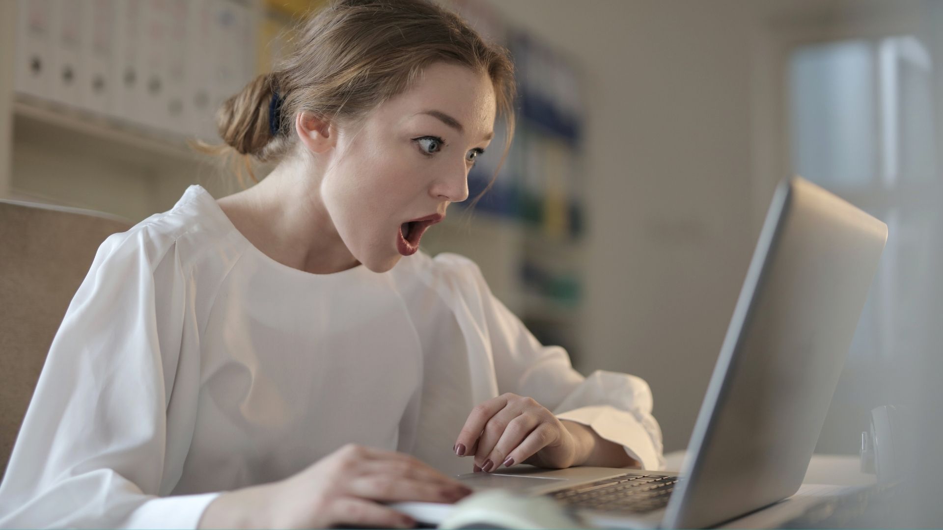 Femme surprise devant son écran d'ordinateur